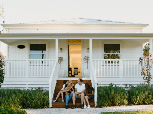 Happy family with their dog sitting on the steps of their home. - Australian Stock Image
