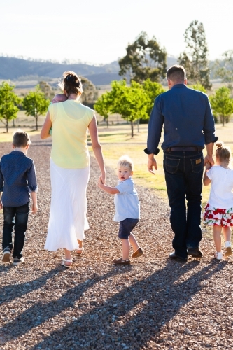 Happy family with young kids walking down driveway - Australian Stock Image