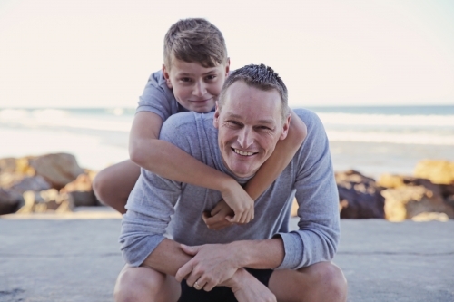 Happy father and teen son on the beach