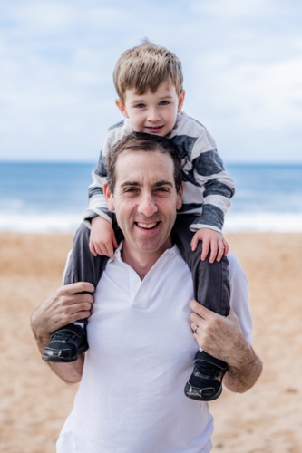Happy father with his son enjoying a fun day at the beach, creating joyful memories together - Australian Stock Image
