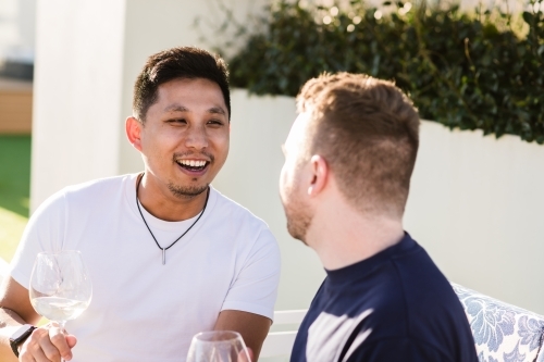 Happy gay couple enjoying a glass of wine outside - Australian Stock Image
