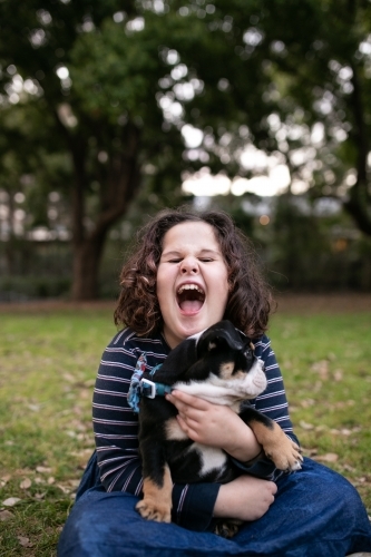 Happy girl outside holding pet bulldog puppy