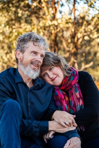 Happy husband and wife sitting together outside - Australian Stock Image