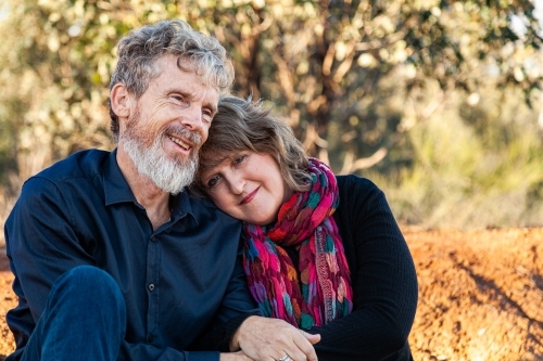Happy husband and wife sitting together outside - Australian Stock Image