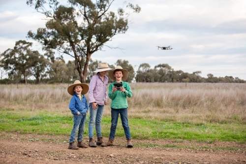 Happy kids using a drone on a farm - Australian Stock Image