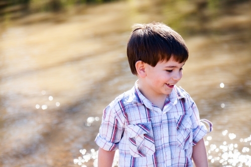 Happy little boy smiling beside river - Australian Stock Image