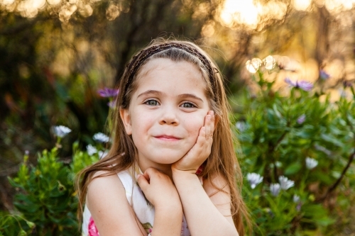 Happy little girl sitting outside in the garden - Australian Stock Image