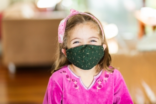happy little girl wearing face mask indoors - Australian Stock Image