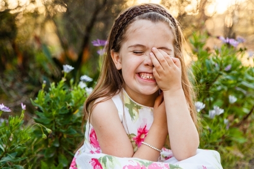 Happy little girl with her hand over face - Australian Stock Image
