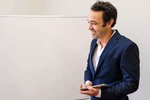 Happy male businessman standing in front of a whiteboard - Australian Stock Image