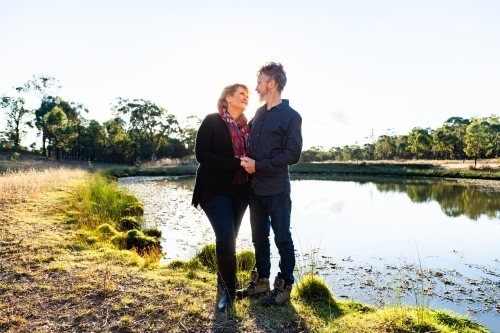 Happy middle aged couple together on farm beside dam - Australian Stock Image