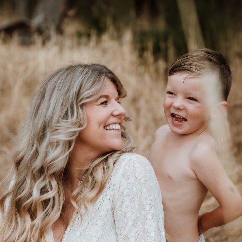 Happy mother and son together in field outside - Australian Stock Image