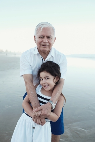 Happy multicultural grandparent with grandchild on the beach - Australian Stock Image