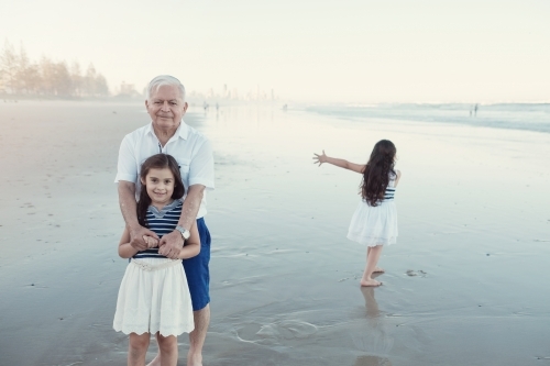 Happy multicultural grandparent with grandchildren on the beach - Australian Stock Image