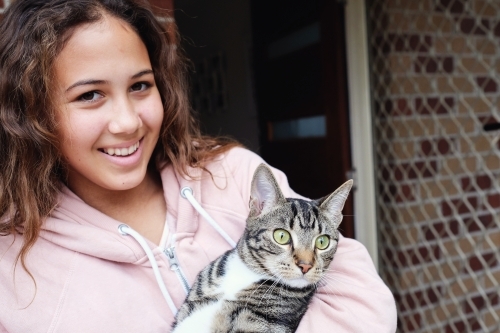 Happy multicultural teen holding cat - Australian Stock Image
