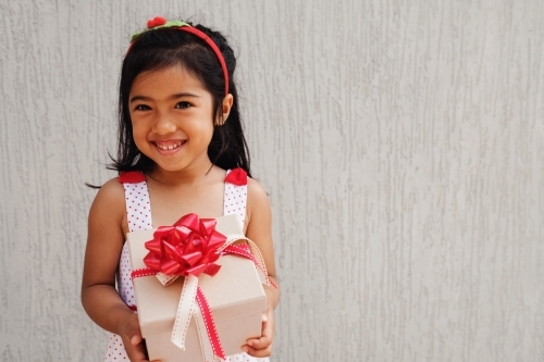Happy multicultural young girl holding present box - Australian Stock Image