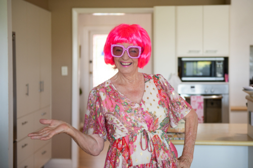 happy older woman wearing a fun pink wig and glasses - Australian Stock Image