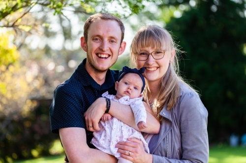 Happy portrait of young family outside in garden - Australian Stock Image