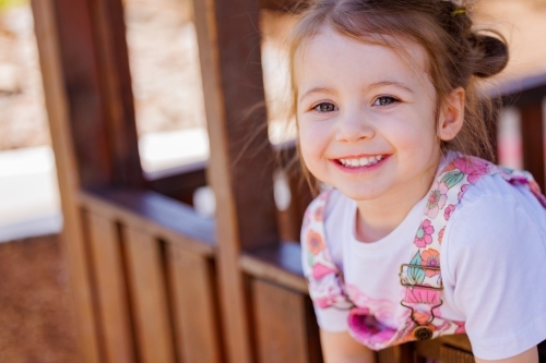 Happy preschool girl smiling in cubby house at kindergarten - Australian Stock Image