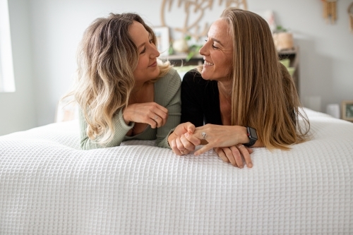 Happy same sex couple lying on a bed looking at one another - Australian Stock Image