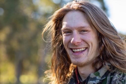 happy smiling young man head and shoulders outdoors - Australian Stock Image