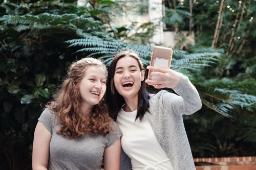 Happy students girl friends using mobile - Australian Stock Image