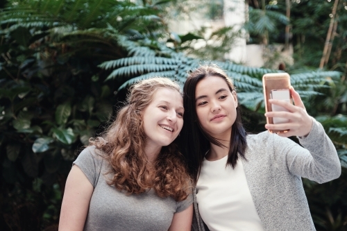 Happy students girl friends using mobile - Australian Stock Image