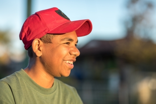 happy teen boy wearing red cap with blurry background