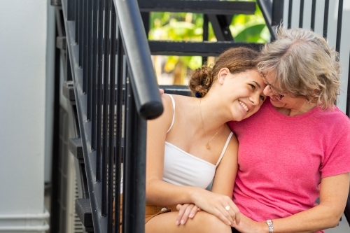 happy teenage girl leaning head on mother's shoulder - Australian Stock Image