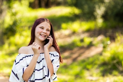 Happy tween girl using her mobile phone outside for a phone call