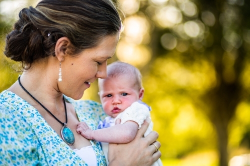 Happy woman holding her newborn daughter outside - Australian Stock Image