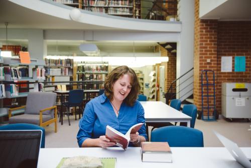 Happy woman reading a book in the university library