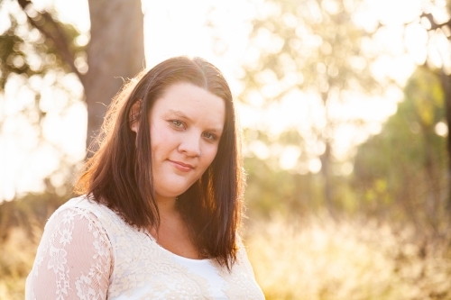 Happy woman standing in bushland in warm golden light - Australian Stock Image