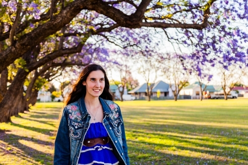 Happy woman walking through park in spring wearing a blue jacket