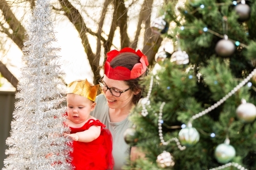 Happy woman with baby experiencing Christmas wonder and tree sparkles at baby's first christmas - Australian Stock Image
