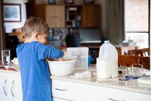 Happy young boy baking in the kitchen - Australian Stock Image