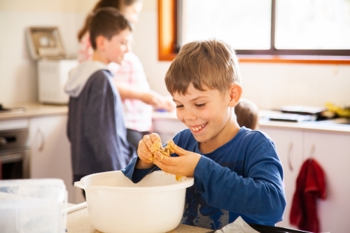 Happy young boy baking in the kitchen - Australian Stock Image