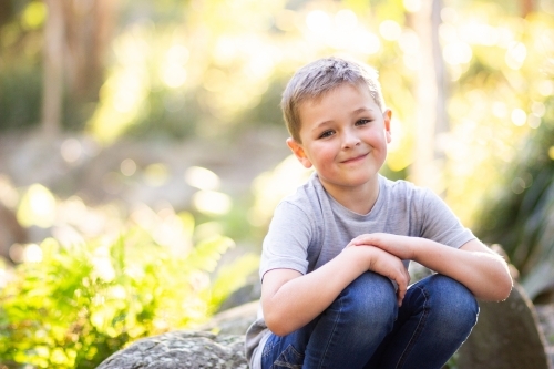 Happy young boy in park beside creek with copy space - Australian Stock Image