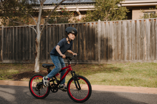 Happy young boy riding his bicycle on the street. - Australian Stock Image