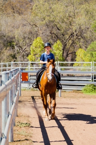 Happy young boy riding horse outside - Australian Stock Image