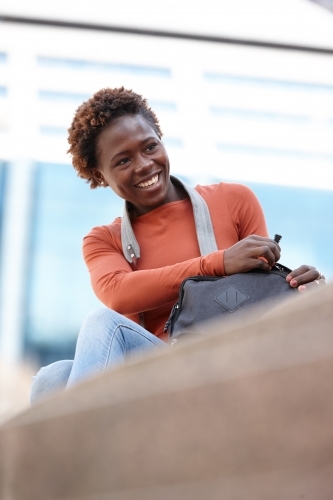 Happy young female photographer opening bag in city - Australian Stock Image
