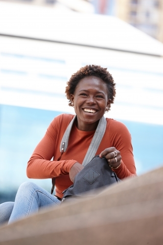 Happy young female photographer opening bag in city - Australian Stock Image