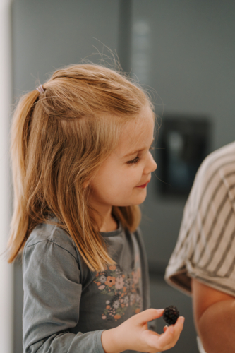 Happy young girl eating blackberry in the kitchen. - Australian Stock Image