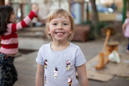 Happy young girl smiling in a preschool setting - Australian Stock Image