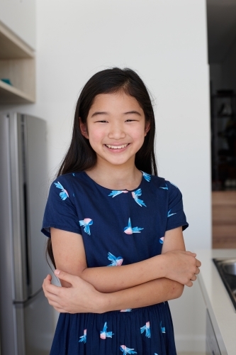 Happy young Japanese girl in kitchen - Australian Stock Image