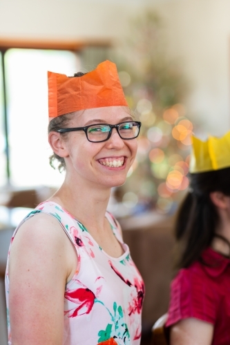 Happy young person celebrating Christmas day smiling and wearing paper crown - Australian Stock Image