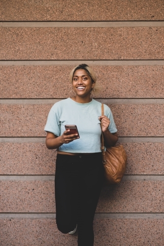 happy young student leading against wall - Australian Stock Image