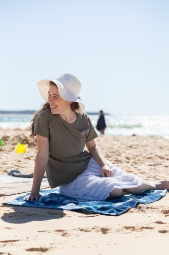Happy young woman in sunhat on bright beach - Australian Stock Image