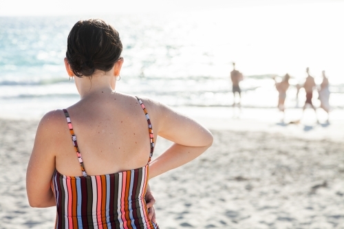 Happy young woman on sunlit beach in summer wearing swimmers - Australian Stock Image