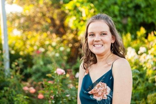 Happy young woman smiling in rose garden - Australian Stock Image